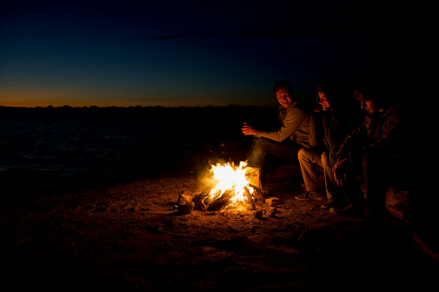 The family gathered around a beach fire at night